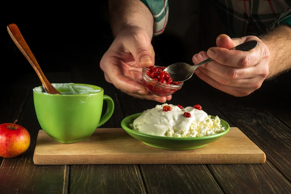 cook-with-spoon-add-sweet-jam-milk-yogurt-cheese-kitchen-black-table-while-preparing-diet-meal